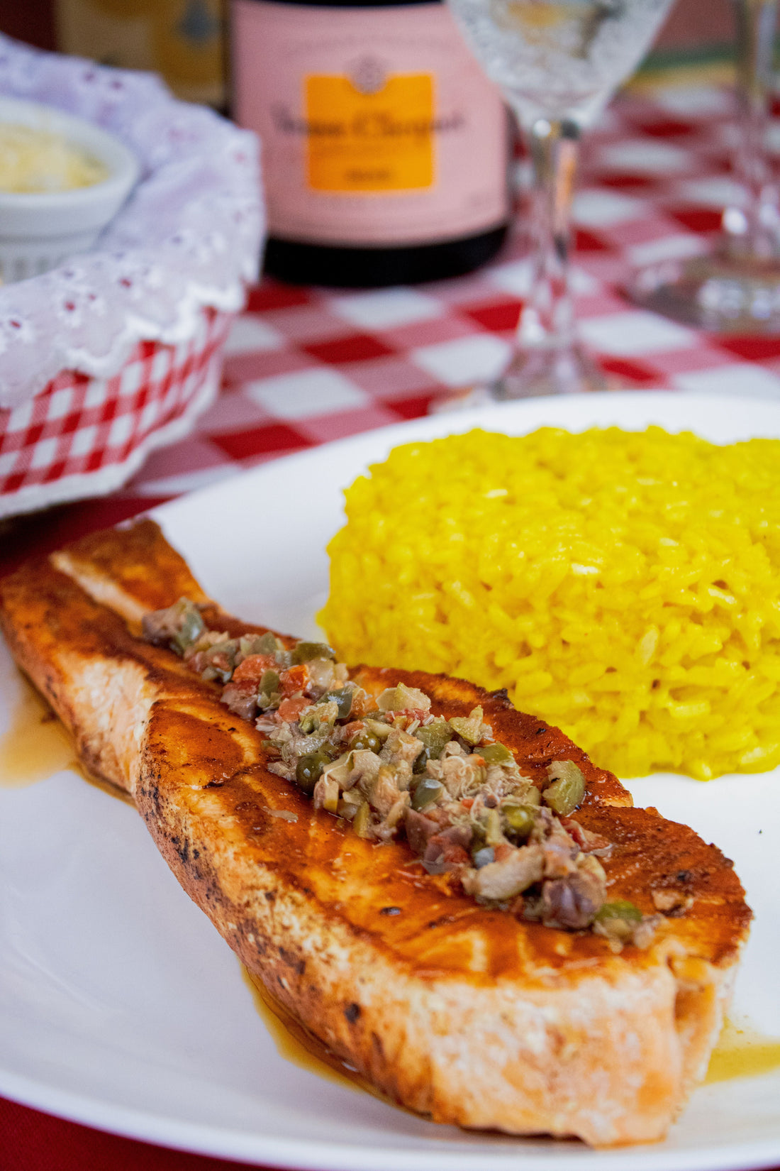 Close-up of grilled salmon topped with herbs served with vibrant saffron rice.
