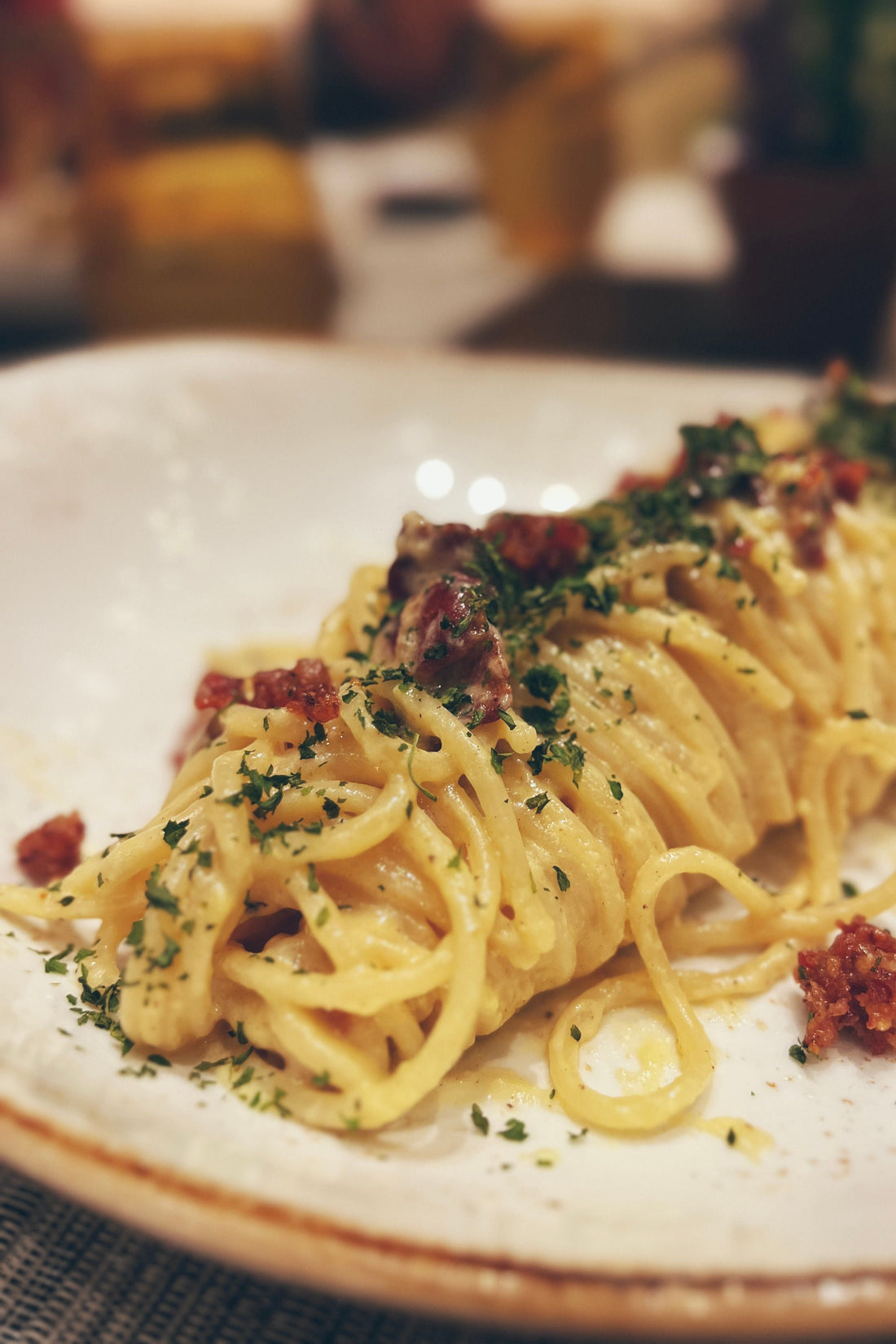 Close-up of creamy spaghetti carbonara with herbs and bacon garnish with Saffron
