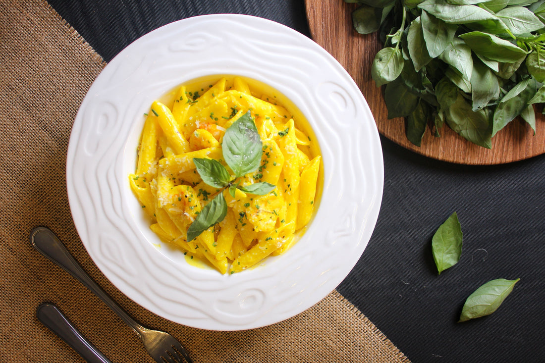 A bowl of golden saffron cream pasta sauce with fettuccine, garnished with fresh herbs and Parmesan, with saffron threads on top